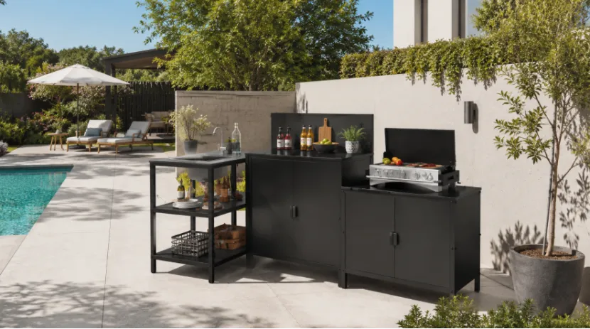 Modern black outdoor kitchen cabinets with a grill and sink by a poolside